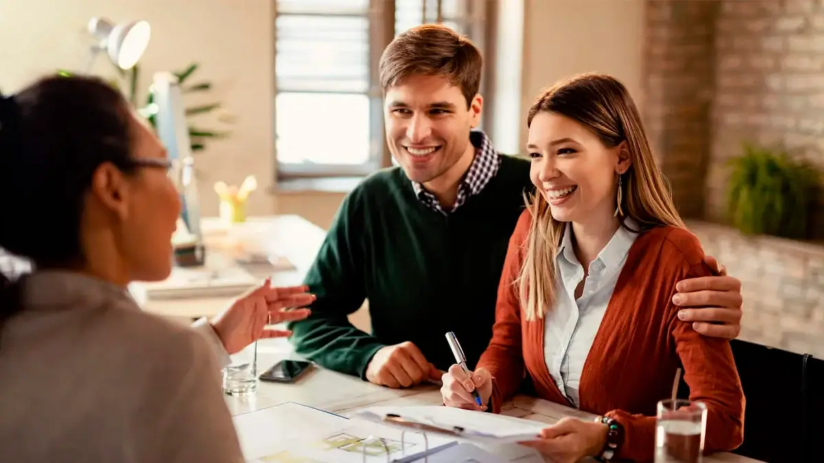 Sem Título 1 0116 Couple Smile At Advisor Across The Table While Signing Document.jpg